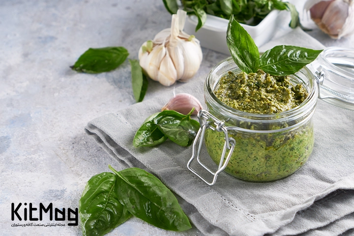 سس پستو مخصوص پاستا با سس پستو که داخل یک جار در دار ریخته شده و روی میز رستوران قرار گرفته است