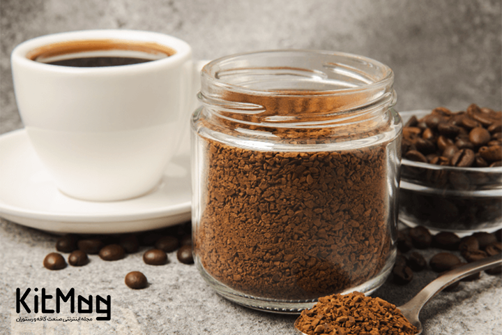 jar of instant coffee alongside a cup of black coffee alongside a small bowl of coffee beans
