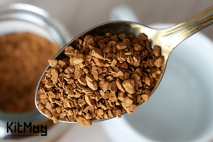 tea spoon full of instant coffee with a jar of instant coffee in the background