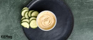 طرز تهیه سس آیولی اسپایسی لیمویی بنر مقاله ظرف سس تک نفره داخل ظرف استون ور مشکی طوسی به همراه اسلایس های خیار