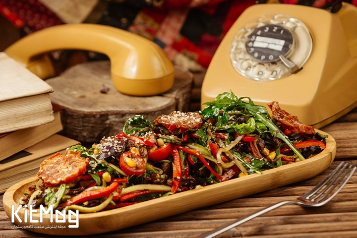 یک سالاد آماده سرو داخل یک سینی چوبی در رستوران برای سرو مشتری آماده شده است