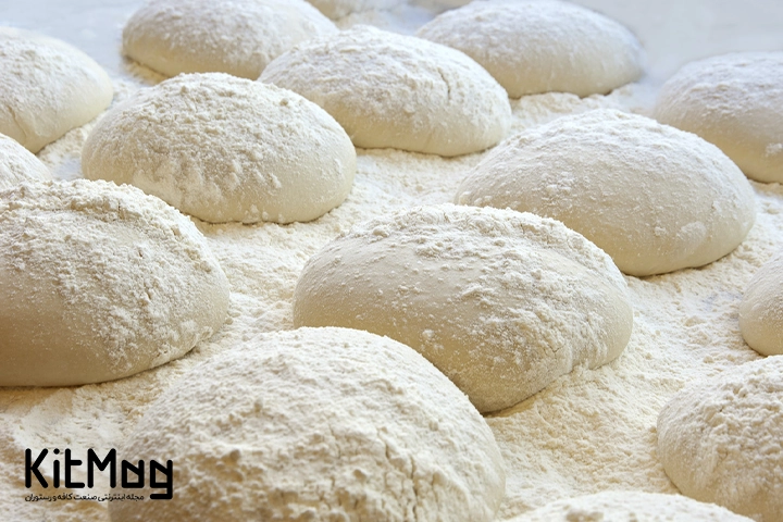 چانه های خمیر پیتزا که روی یک تخته ریخته شده است و آماده برای پخت نان یا پیتزا می باشد