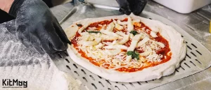 اشتباهات رایج در تهیه خمیر پیتزا چیست؟ یک آشپز در حال پهن کردن خمیر پیتزا روی پارو پیتزا