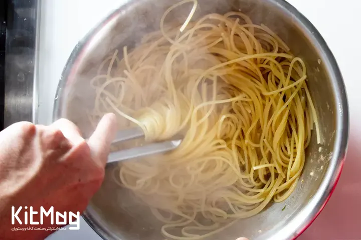 سرو پاستا توسط انبر های مخصوص در بشقاب مشتریان .