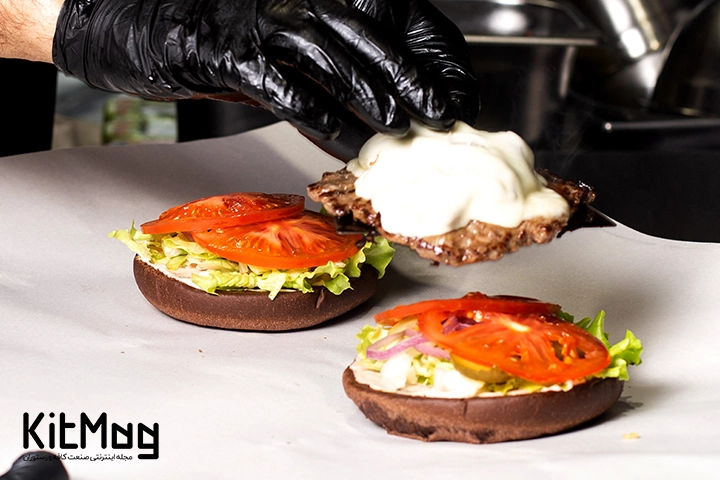 آشپز در حال آماده سازی همبرگر اسمش برگر که نان آن کنجدی می باشد