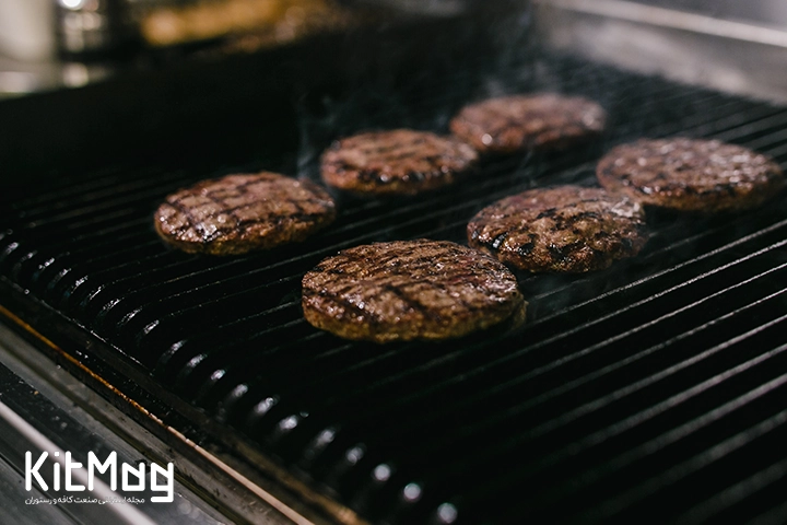 شش عدد برگر که روی گریل گازی قرار گرفته است