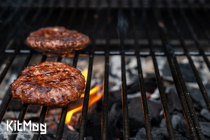 گوشت همبرگر که روی گریل ذغالی قرار گرفته است از نمای نزدیک