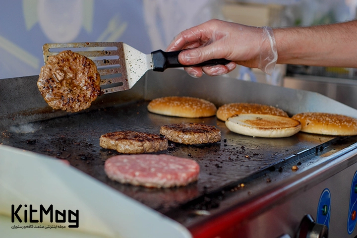 انواع همبرگر های دست ساز که روی گریل برقی قرار گرفته است و نان آن در حا کبابی شدن است 