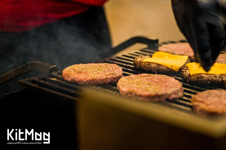 گریل ذغالی که برگر ها به همراه سیب زمینی روی آن قرار گرفته است