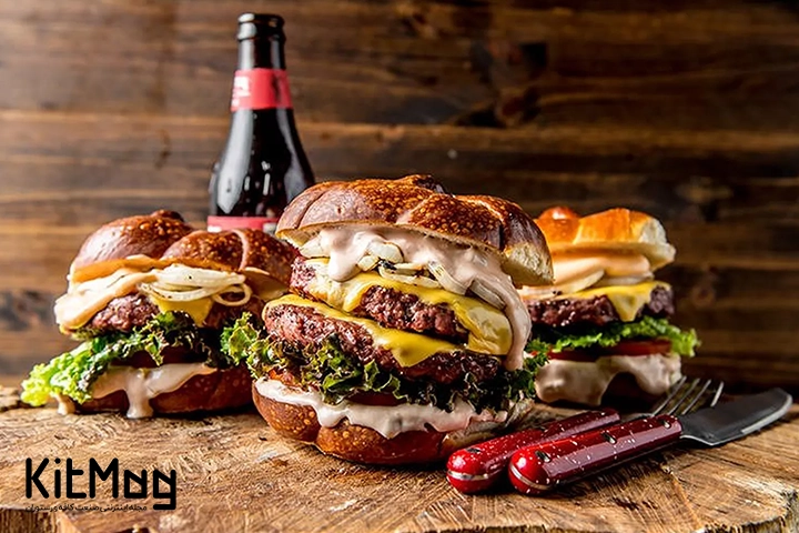 سه عدد همبرگر اسموکی برگر روی یک تخته چوبی 