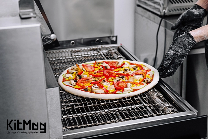 آشپز در حال قرار دادن پیتزا در فر ریلی پیتزا می باشد از نمای نزدیک
