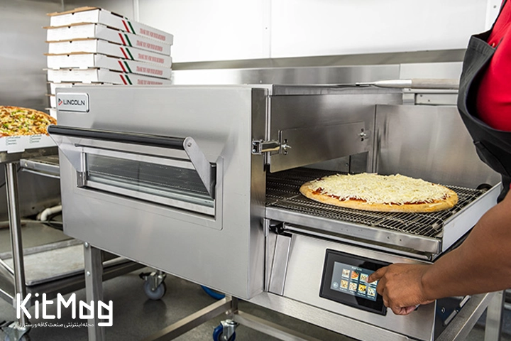 آشپز مغازه فست فود در حال  پخت پیتزا و قرار دادن خمیر پیتزا با تاپینگ داخل فر پیتزا