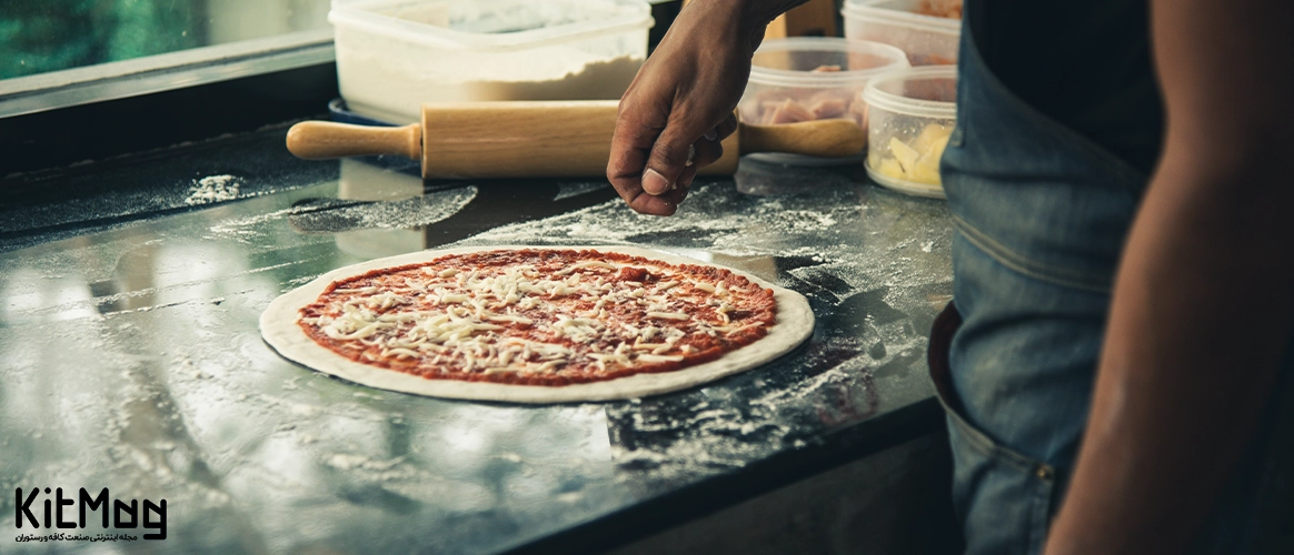 پهن کردن خمیر پیتزا آشپز در حال پهن کردن خمیر پیتزا می باشد