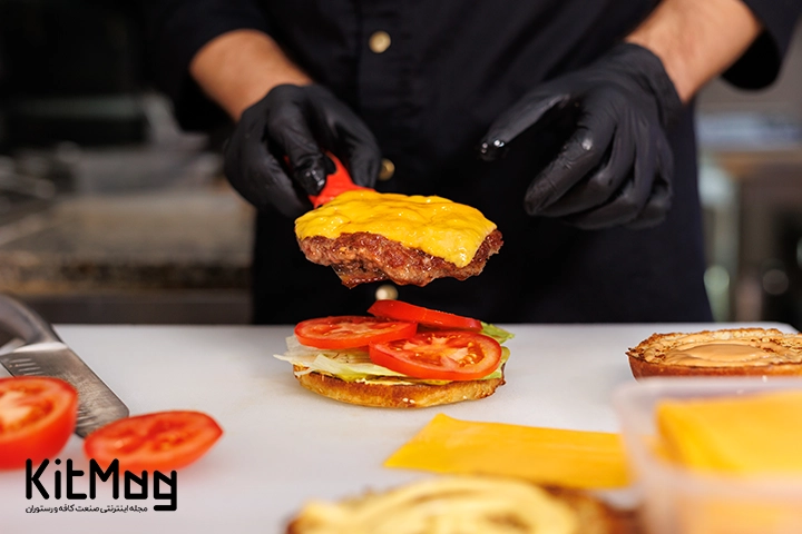 یک گوشت همبرگر که روی آن پنیر چدار زرد قرار گرفته است و لایه زیرین برگر گوجه های اسلایس شده قرار گرفته است