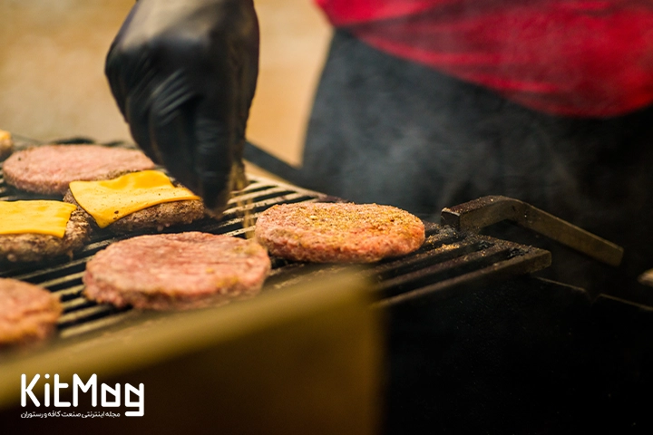 آشپز در حال پخت همبرگر روی گریل گازی می باشد