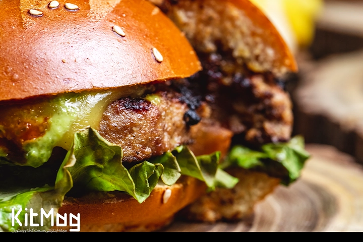 یک همبرگر برش خورده که از نمای بغل آن از نزدیک عکس گرفته شده است