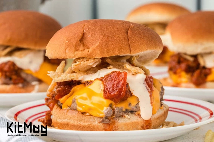 یک چیز برگر که سیب زمینی و پنیر چدار از آن بیرون زده از نمای نزدیک و داخل یک بشقاب قرار گرفته است