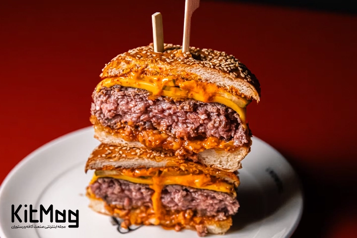 یک عدد همبرگر که از وسط نصف شده است و روی یکدیگر قرار گرفته است و از وسط سیخ چوبی مخصوص همبرگر از داخل آن رد شده است
داخل این چیزبرگر با دو لایه پنیر چدارپر شده است