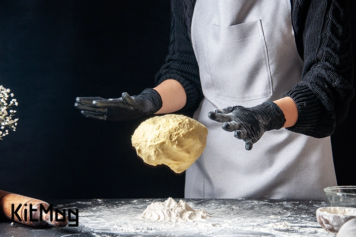 آشپز در پیتزا فروشی در حال پهن کردن خمیر پیتزا می باشد پس زمینه آن مشکی می باشد