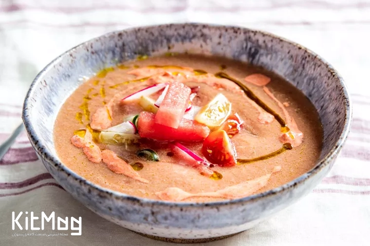 کاسهای سرامیکی از گاسپاچوی سرد هندوانه که روی آن کرمای فلفل کالابریایی ریخته شده است.