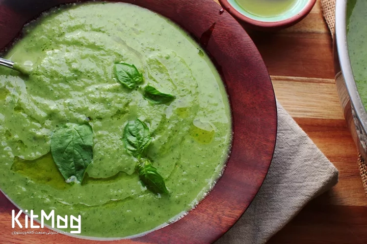 کاسهای از سوپ سبز روشن کدو سبز و ریحان که با برگهای تازهٔ ریحان تزیین شده است