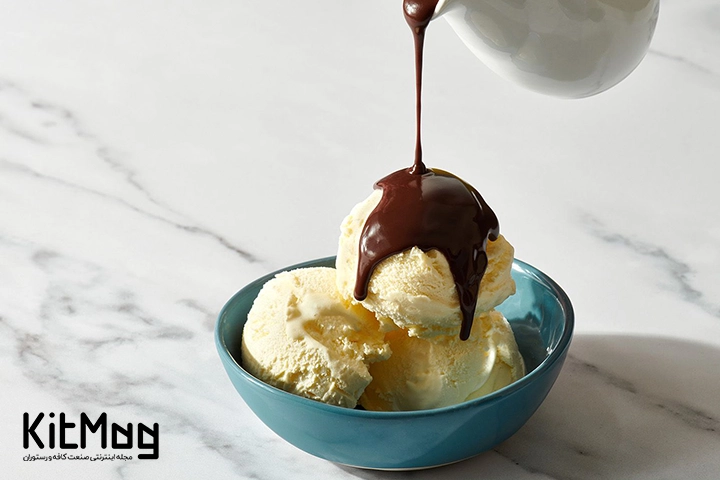 یک ظرف سرامیکی که داخل آن یک اسکوپ بستنی قرار گرفته است و آشپز در حال ریختن سس تاپینگ یا سس غلیظ شکلاتی روی بستنی می باشد