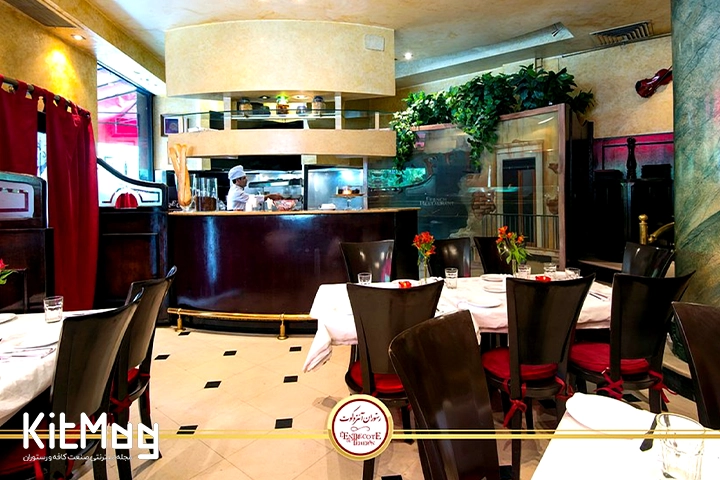 نمای داخلی رستوران آنتروکوت که با صندلی های چوبی میزهای کلاسیک نمای قدیمی و نوستالژی دیده می شود و سرآشپز پشت کانتر در حال درست کردن غذاهای مختلف برای آماده سازی می باشد