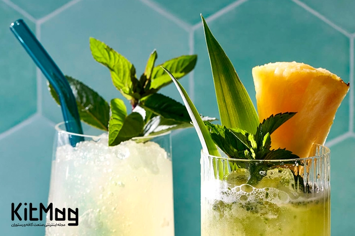 موکتل کولر آناناس و نعناع (Pineapple Mint Cooler) که داخل یک لیوان ریخته شده است و با تکه های آناناس، نعناع و برگ آناناس تزئین و گارنیش شده است