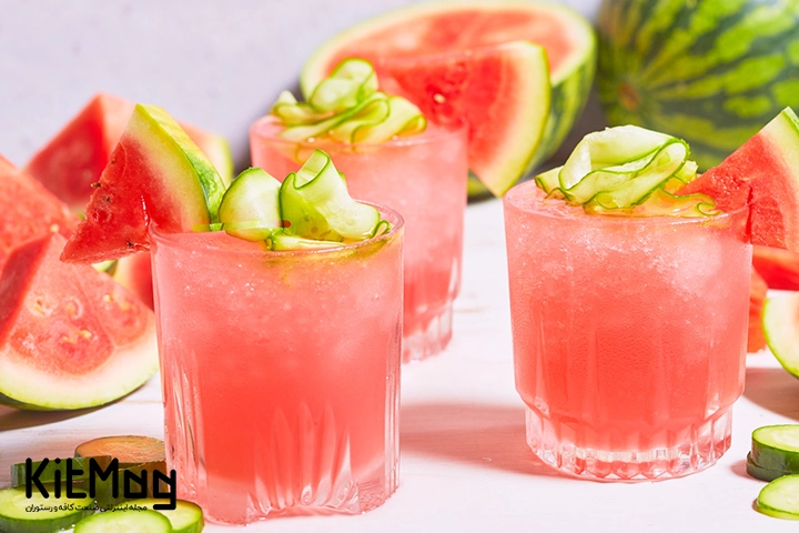 موکتل خنک هندوانه و خیار (Watermelon Cucumber Cooler) که داخل یک لیوان پایه کوتاه ریخته شده و دور لیوان با خیار و هندوانه تزئین شده است