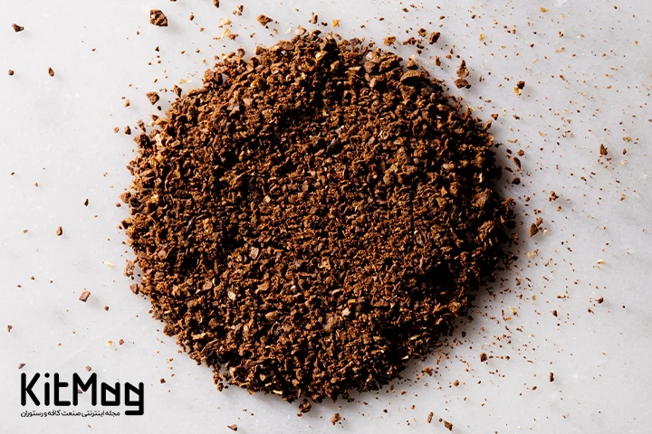 آسیاب متوسط  (Medium Ground Coffee) که دانه های آسیاب شده این قهوه روی یک میز سفید ریخته شده است