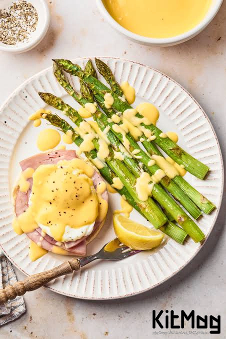 یک بشقاب که در آن مارچوبه پخته شده به همراه لیمو ترش برش خورده و eggs Benedict نوعی تخم مرغی به همراه ژامبون در یک ظرف سفید دیده می شود