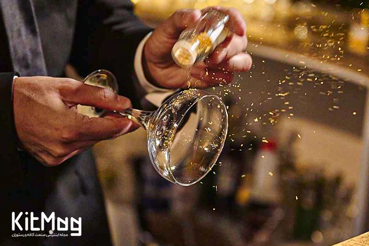 بارتندر که از نمای نزدیک در حال پاشیدن پودر طلا روی یک لیوان مارگاریتا می باشد تا آن را برای نوشیدن کوکتل آماده کند 