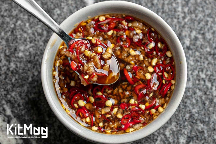 سس محبوب چیلی که در یک ظرف ریخته شده است و روی یک میز سنگی قرار گرفته است که محصولی بدست آمده از کشور های آسیایی می باشد و داخل آن با فلفل قرمز پر شده است