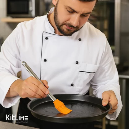 با استفاده از قلمو سیلیکونی دسته استیل ۲۵.۵ سانتیمتری در حال چرب کردن سینی پخت